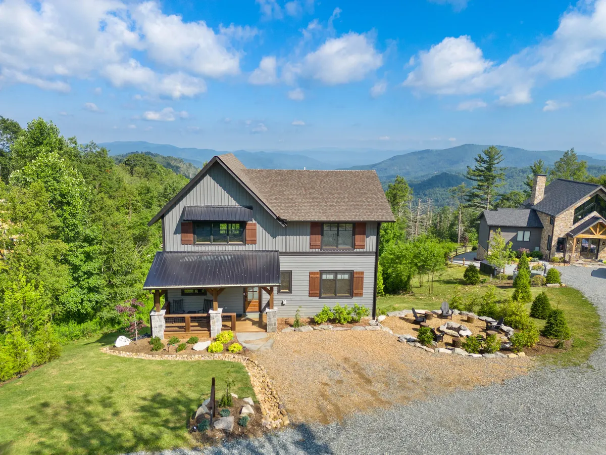 The modern exterior of the house, featuring landscaped stonework and an inviting outdoor seating area. The structure's clean lines emphasize contemporary comfort, and the setting showcases a harmonious relationship with the surrounding natural landscape.